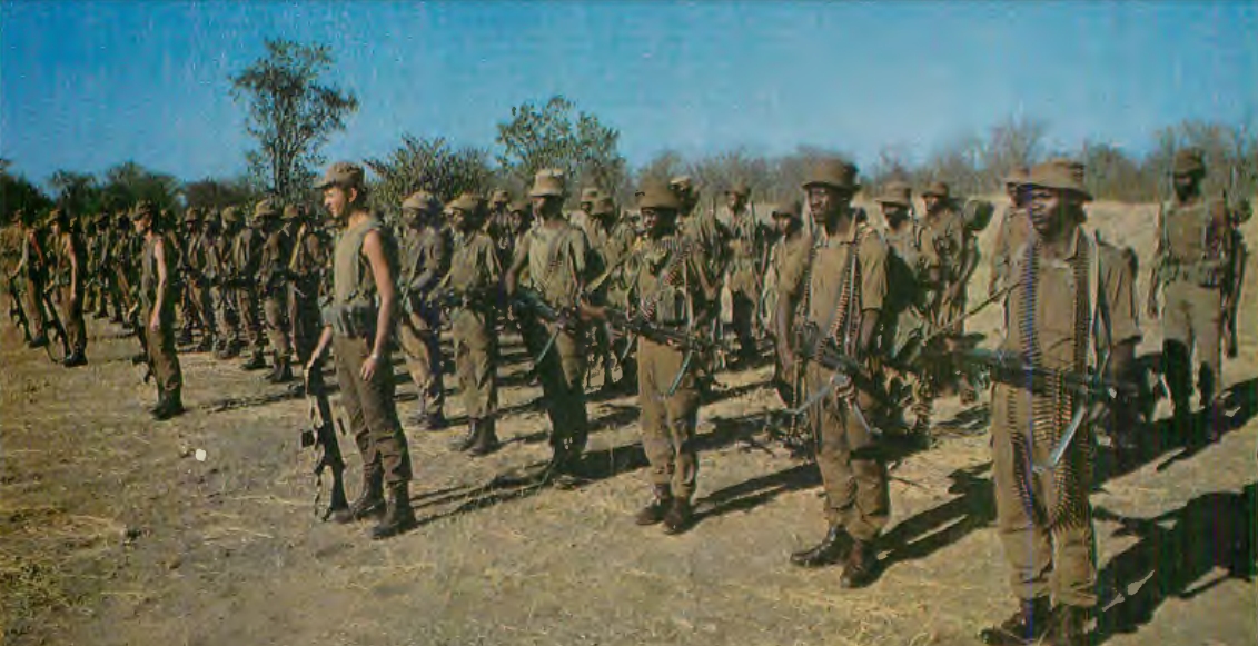 Ovambo troops and their South African officers await pre-patrol inspection at forward base camp in S.W. Africa. Note preponderence of light machine guns in this and other photos . S. African Army units seem to carry double the number of machine guns as their NATO counterparts. 